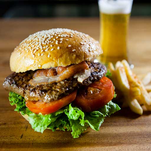 A delicious burger on a sesame bun with lettuce, tomato, and bacon.