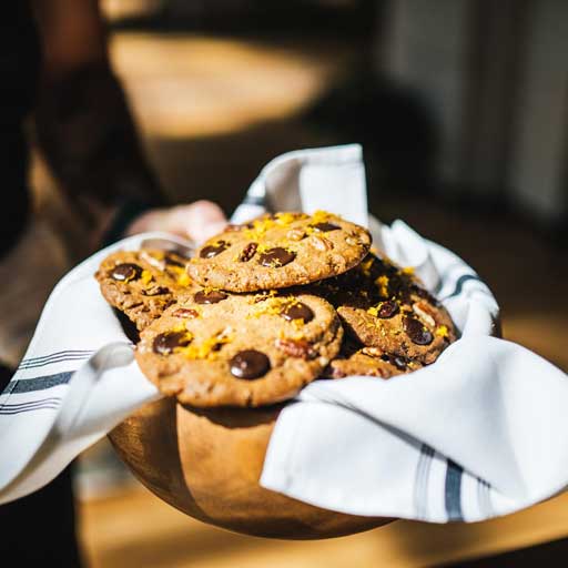 A batch of homemade chocolate chip cookies presented in a napkin-covered wooden bowl.
