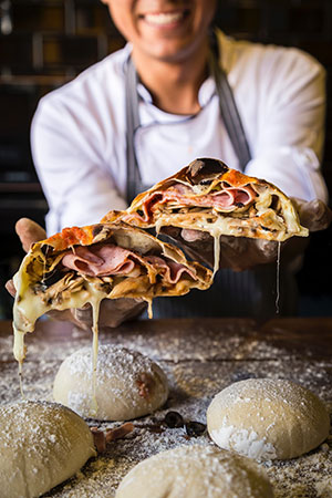 A photo of Taril Coleman, founder, holding up some slices of freshly made pizza.