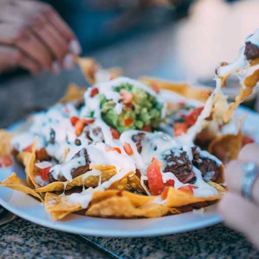An appetizer of nachos being shared by several people.